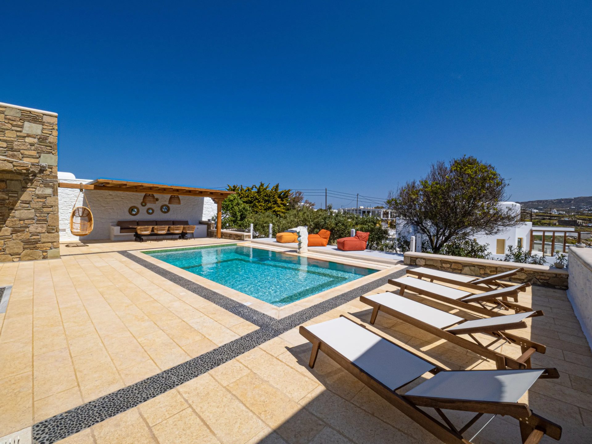 Pool terrace with sun loungers at Villa Gaia in Psarou, Mykonos