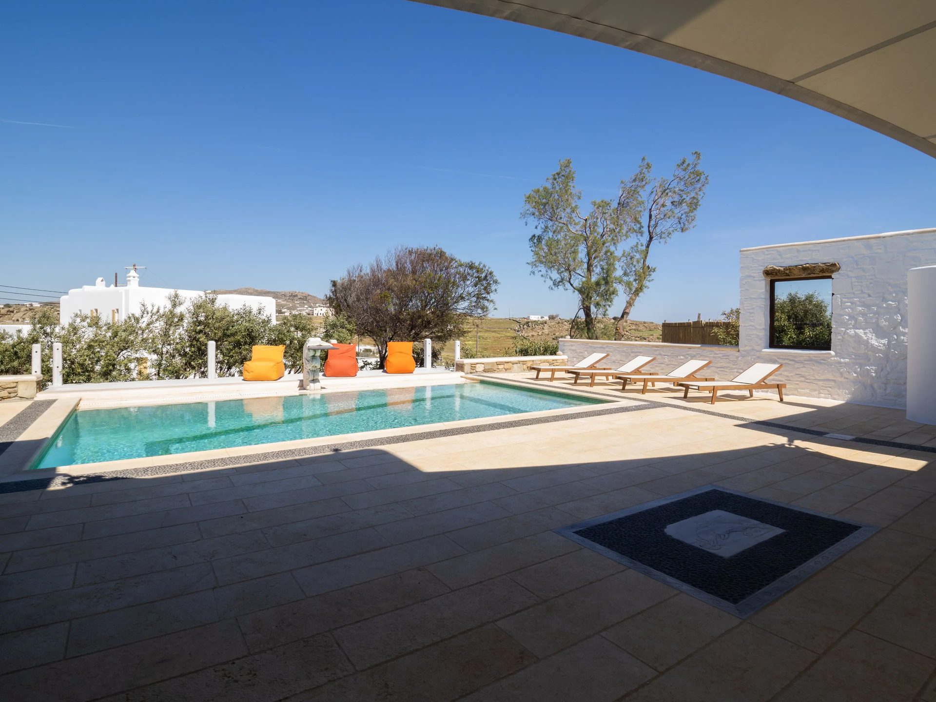 Pool terrace from the shaded veranda at Villa Gaia in Psarou, Mykonos