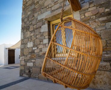 Hanging rattan chair by the stone wall at Villa Gaia in Psarou, Mykonos