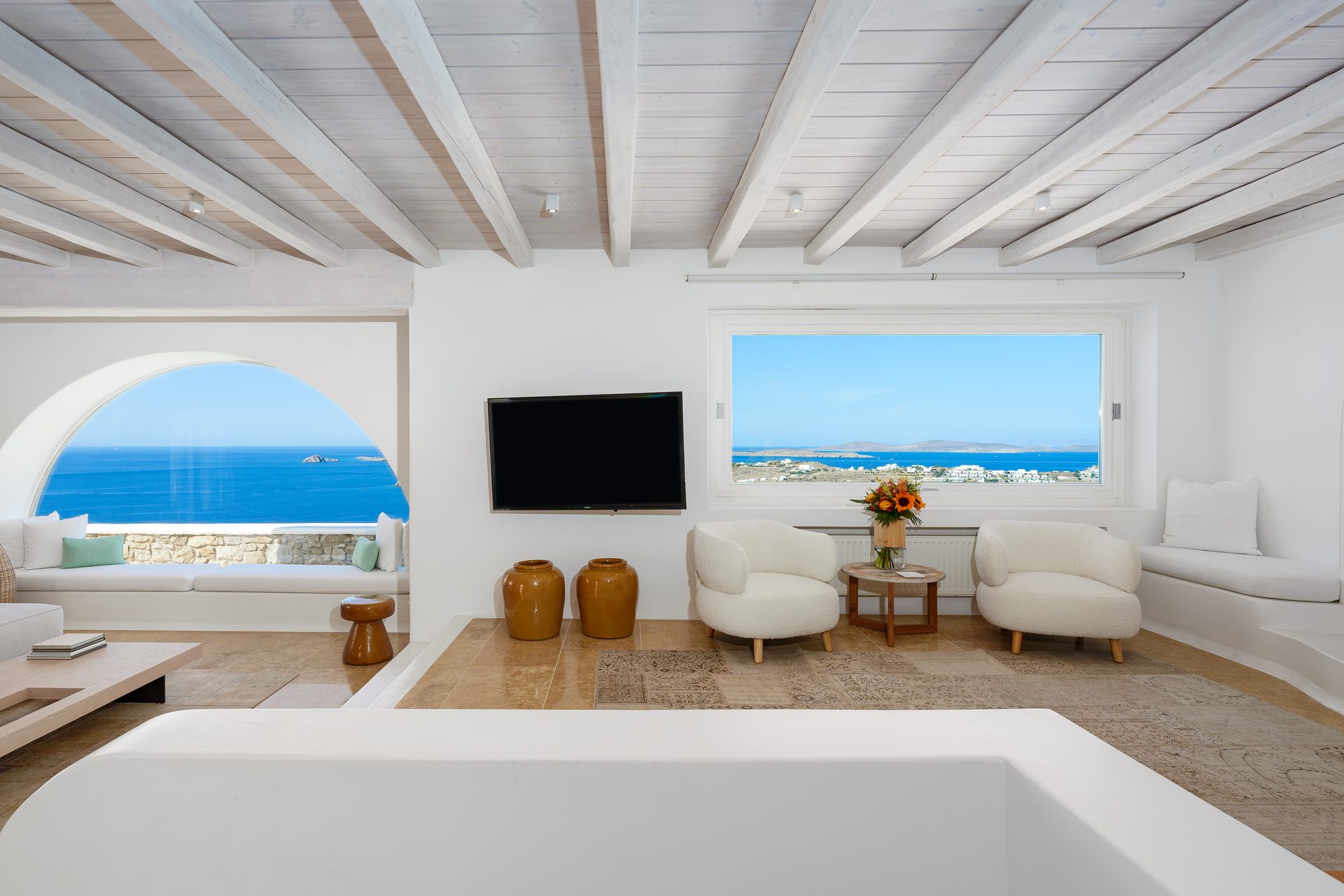 Living room with arched sea-view windows at Villa Kymothea in Agios Lazaros, Mykonos