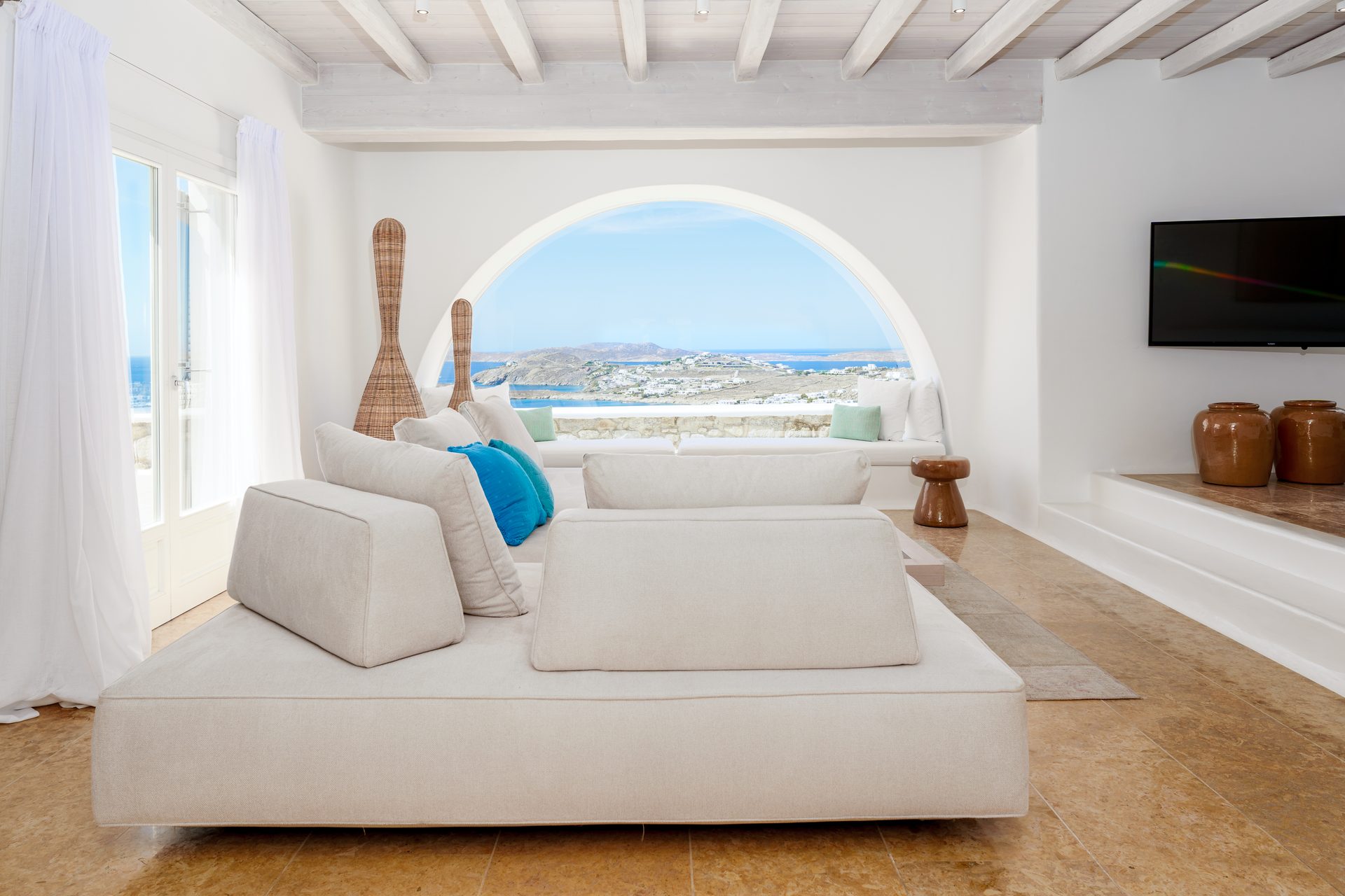 Lounge with arched sea-view window at Villa Kymothea in Agios Lazaros, Mykonos