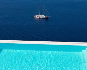 Pool and sailing yacht in the bay at Villa Kymothea in Agios Lazaros, Mykonos