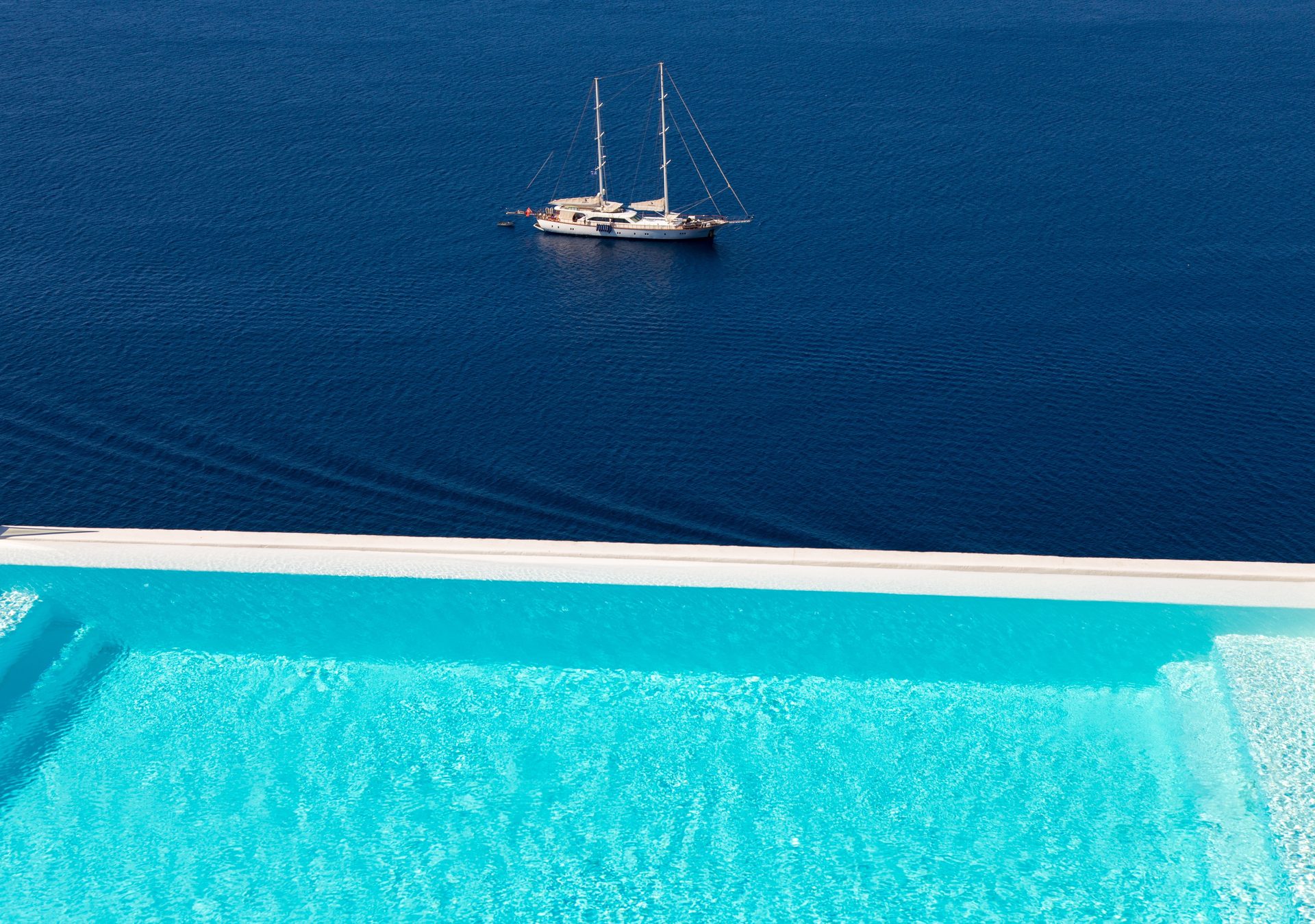 Pool and sailing yacht in the bay at Villa Kymothea in Agios Lazaros, Mykonos
