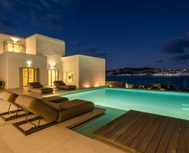 Pool at dusk with town lights at Villa Mare Blu in Kanalia, Mykonos