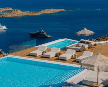 Pool deck with parasols and yachts in the bay at Villa Nafsithoi in Agios Lazaros, Mykonos