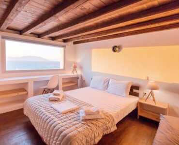 Bedroom with sea-view window at Villa Phaedra in Pouli, Mykonos