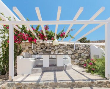 Pergola dining area with stone walls at Villa Phaedra in Pouli, Mykonos