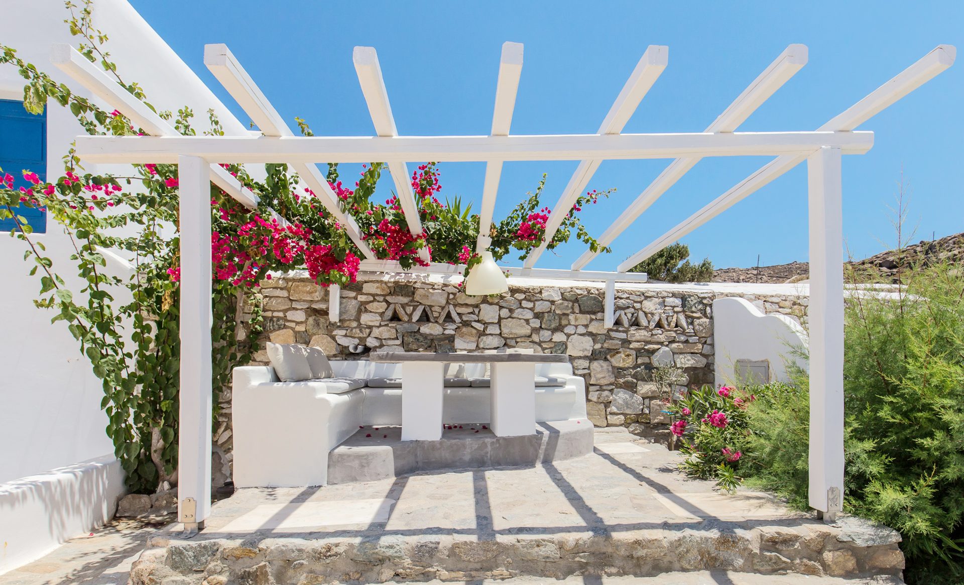 Pergola dining area with stone walls at Villa Phaedra in Pouli, Mykonos