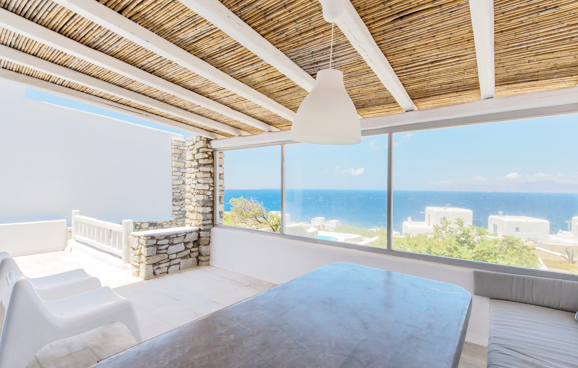 Dining area with sea-view windows at Villa Phaedra in Pouli, Mykonos