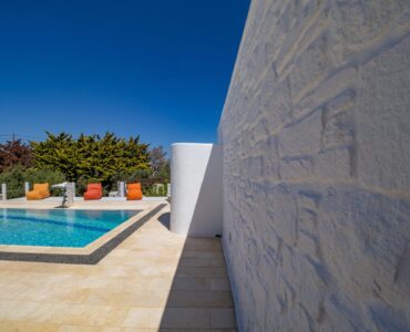 Pool beside the whitewashed wall at Villa Uranos in Psarou, Mykonos
